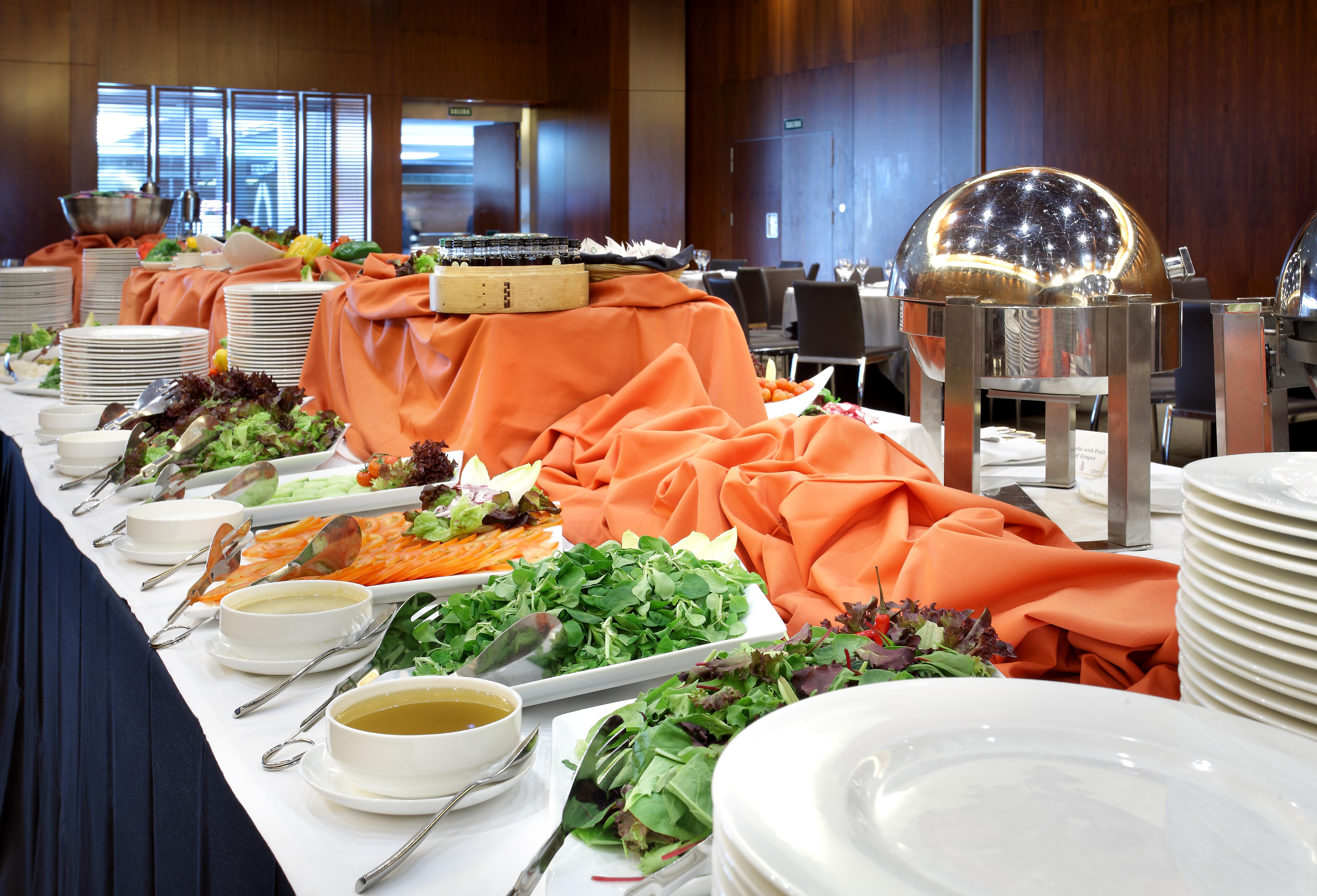 Hotel Eurostars Madrid Tower Esterno foto The photo shows a buffet table set up for a meal. The table is covered with an orange cloth and features a variety of food items. There are platters of greens and salads, as well as bowls of soup or dressing. A metal chafing dish is present, likely c