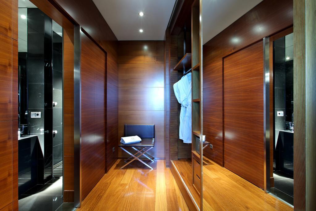 Hotel Eurostars Madrid Tower Esterno foto The photo shows a stylish interior space that appears to be a modern changing area or dressing room. The walls are made of polished wood, giving a warm, elegant feel. There are several closed doors, indicating private spaces such as lockers or bathro