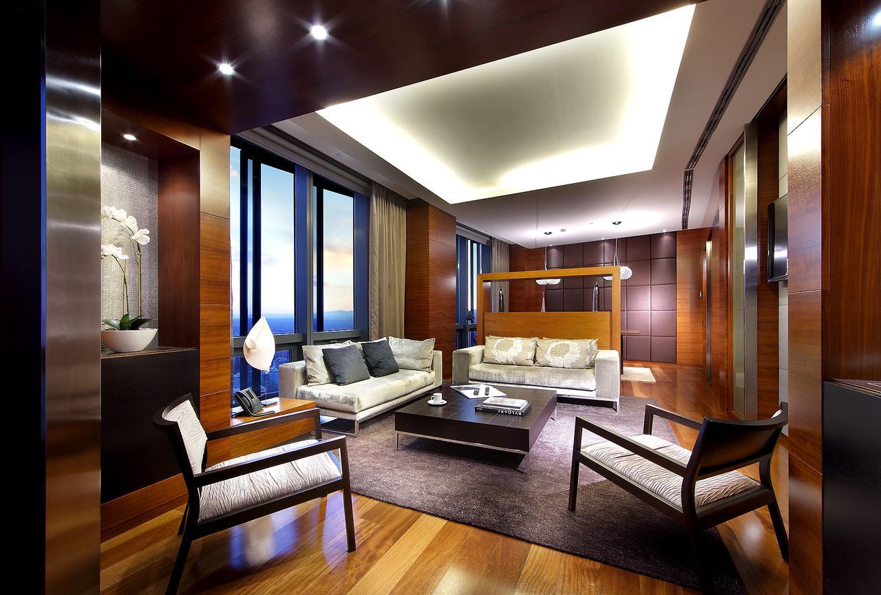 Hotel Eurostars Madrid Tower Esterno foto The photo depicts a modern and elegantly designed living room. The space features large windows that allow natural light to flood in, showcasing a beautiful view outside. The flooring is polished wood, and the color palette incorporates warm tones, i
