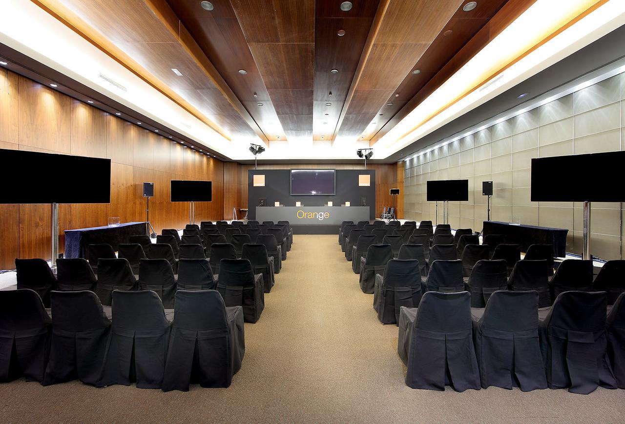 Hotel Eurostars Madrid Tower Esterno foto The photo shows a conference room set up for an event. It features rows of black chairs arranged facing a central stage or podium area. There are large screens on either side of the room, suggesting that presentations or visual displays may be part o