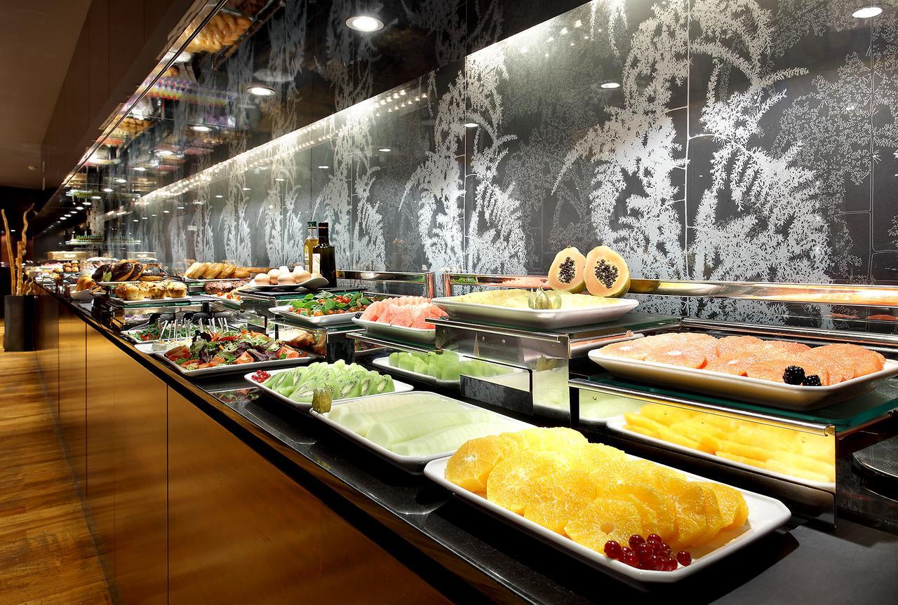 Hotel Eurostars Madrid Tower Esterno foto The photo shows a buffet display featuring a variety of dishes and ingredients. There are plates filled with different types of food, including seafood, fruits, and vegetables. The arrangement is visually appealing, with the food presented on glass s