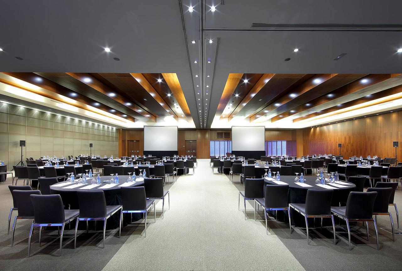 Hotel Eurostars Madrid Tower Esterno foto The photo shows a large conference or meeting room. It features multiple round tables set with chairs arranged around them, indicating that it is prepared for a formal gathering or event. Each table has water bottles and possibly notepads, suggesting