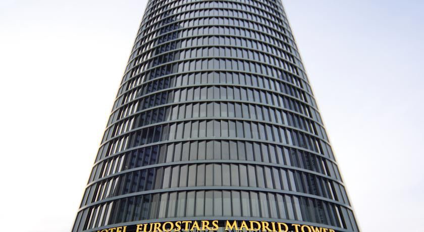 Hotel Eurostars Madrid Tower Esterno foto The photo displays a tall, modern skyscraper known as the Eurostars Madrid Tower. The building features a sleek, glass facade with a cylindrical design. At the base, there's a prominent sign indicating the name of the hotel, “Eurostars Madrid Tower,”