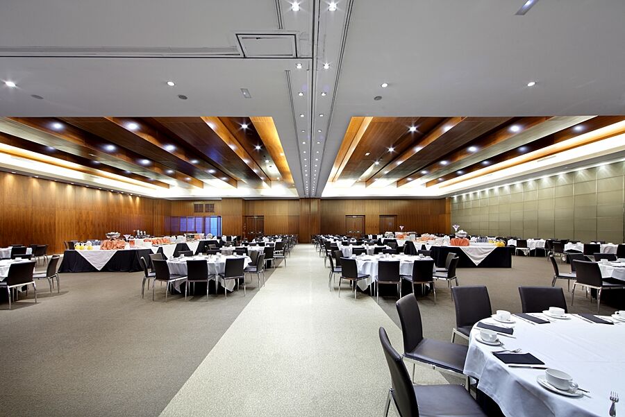 Hotel Eurostars Madrid Tower Esterno foto The photo depicts a spacious banquet hall or conference room. It features a series of tables arranged in a grid pattern, covered with white tablecloths and adorned with black tablecloths at the edges. Each table is set with plates, cutlery, and glass
